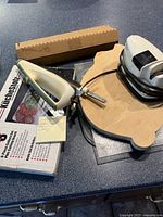 Photo showing KitchenAid sharpener box, metal and plastic sharpener attachment, white electric carver with no plug, and wooden cutting board shaped like pig