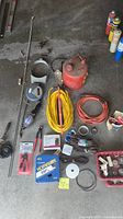 Overview of assorted electrical supplies spread on garage floor including extension cords, antique gas can, tools, and wires.