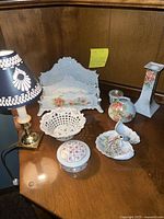 Full lot photo of floral ceramic desk set pieces and small lamp on wooden surface