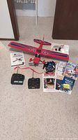 Photo showing entire lot including ParkZone model airplane, two remotes, charger, and multiple literature items on carpeted floor.