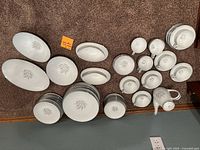 Full set of Noritake china including plates, bowls, cups, saucers, and serving pieces laid out on floor.