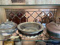 Three items on glass shelf: left covered casserole, center shallow bowl, right covered bowl