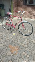 Full side view of the vintage red Schwinn Speedster bicycle showing frame, handlebars, wheels, saddle and front fender.