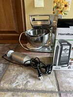 Hamilton Beach Deluxe Mixer showing tilt-head and stainless steel bowls, Hamilton Beach can opener box, and Cuisinart Quick Prep immersion blender.