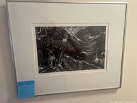 Frontal view of black and white gelatin silver print, matted and framed with a white frame, showing abstract textured and reflective surfaces.