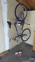 Blue Trek Antelope Trek 830 bicycle hanging upside down, showing full frame and tires, in garage with concrete floor and wooden cabinetry nearby