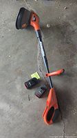 Full view of Black & Decker cordless trimmer/edger with two batteries on concrete floor.