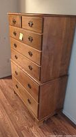 Wooden 7 drawer dresser showing left side and top drawers, overall in good condition with light scratches visible.