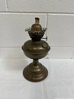 Side view of antique brass kerosene lamp showing wick and burner.