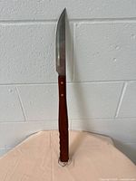 Full view of BBQ cutting utensil showing stainless steel blade and wooden handle