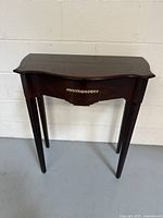 Front view of the Bombay mahogany console table showing the curved top and brass decor on the drawer front.