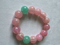 Top-down view of the flexible beaded bracelet showing pink and green round beads on an elastic string.