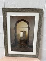 Frontal view of the wooden frame containing a photo of multiple stone archways extending in perspective, showing the frame texture and photo content.