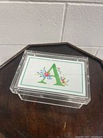 Top view showing clear plastic box with removable lid featuring a colorful floral design and large green letter A.