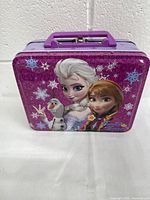 Front view of the Disney Frozen tin handle carrying case with Anna, Elsa, and Olaf graphic.