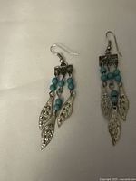 Front view of the turquoise beaded earrings showing the triple silver leaf charms and bead clusters.