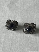 Front view showing flower shaped earrings with rhinestones and central cabochon.