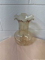 Full view of the vintage beige glass lampshade with a ruffled edge around the top, showing its shape and color.