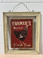 Framed farmhouse style wall decor with distressed wood frame, chicken wire backing, and red painted metal sign of a chicken with 'FARMER'S Market Fresh Eggs' text.