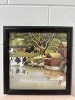 Front view of framed farmhouse scene picture with cows, geese, pelicans, tree, barn, and water wheel.