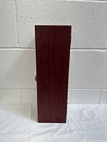 Closed view of the tall rectangular wooden wine bottle gift box, showing dark polished wood grain and metal clasp on front.