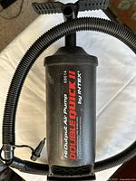 Top view of the black cylindrical Intex air pump showing the Double Quick II branding and model number 68614 on the main body with attached hose and nozzles.