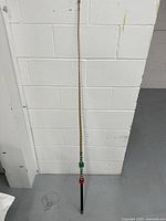 Full view of the 62 inch whip hanging against a white wall, showing its braided shaft and handle.