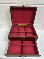 Open top view of the jewelry box showing the upper compartment with six red velvet-lined sections.