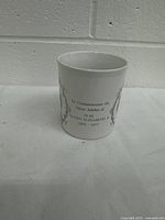 Front of white ceramic commemorative mug with printed text commemorating the Silver Jubilee of Queen Elizabeth II from 1952 to 1977.