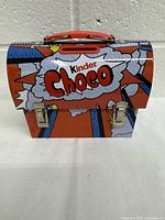 Closed front view of the Kinder Choco branded rigid box shaped like a backpack with colorful comic style graphics and red handle.