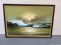 Full frontal photo of the large framed painting showing ocean waves, rocks and sky, with a visible signature on the lower left corner.