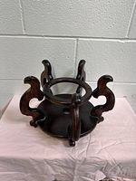 Front angle photo of large vintage Chinese rosewood plant stand showing circular ring top and four ornate legs.