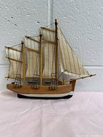 Front view of the wooden model sailing ship with three fabric sails and mounted on a black bracket.