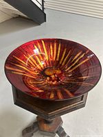 Glass decorative bowl with multicolor abstract pattern in reds, orange, and yellow hues, glossy finish.