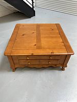 Front view of the Palliser solid wood square coffee table showing top, front, and carved apron details.