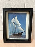 Framed image of the sailing ship Bluenose II under full sails on ocean, set in a black frame.