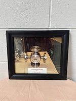 Full view of the black shadow box frame showing the internal mechanical model and identification plaque.