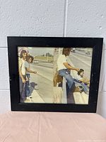 Front view of black wooden picture frame showing retro photo of three people outdoors with a utility pole in the middle.