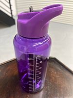 Top portion of translucent purple plastic water bottle showing the flip-top lid with built-in straw.