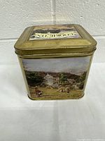 Square metal cookie tin with pastoral rural landscape artwork on the sides and lid. Lid has 'COOKIE TIN' and 'MADE IN ENGLAND' text.