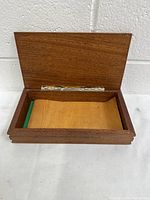 Open view of the wooden cigarette holder showing the interior lighter wood and green felt lining