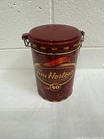 Front view of dark red Tim Hortons 40 Years collectible tin with logo and 40th anniversary emblem.