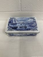 Closed view of the rectangular tin box showing the detailed Dutch nautical scene in blue and white on the lid.