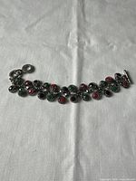 Full view of vintage bracelet with colored rhinestones laid flat on white surface.