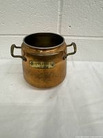 Full view of the vintage copper pot showing overall shape, dual handles, and the patina on the surface.