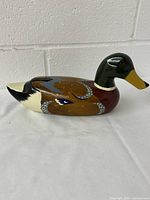 Side view of carved and painted mallard duck decoy showing detailed wing patterns and painted tail.