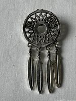 Front view of vintage hippie brooch showing circular sunburst design and four dangling feather charms.
