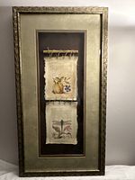 Full view of the framed botanical composition showing two parchment-style illustration sheets suspended inside the frame