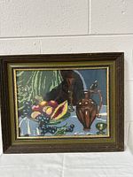 Front view of framed embroidery showing fruit and wine still life scene.