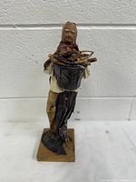 Front view of vintage papier mache folk art figure holding a bowl